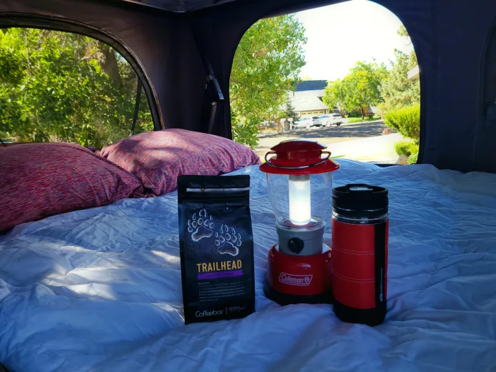RV rental comfort: Trailhead coffee, a Coleman lantern, and GSI mug on cozy bedding with a view of the outdoors.. Mazda Campervan 2018