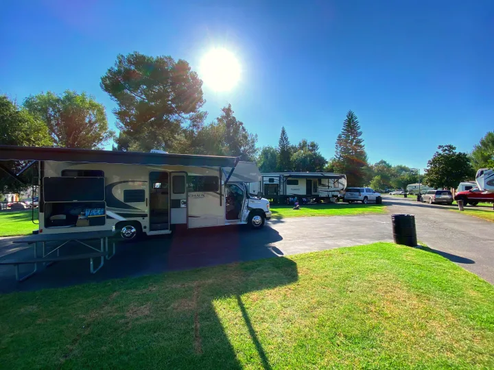 Enjoying the sunshine at an RV park, showcasing an RV rental with an extended awning and a picnic table. Ideal for outdoor adventures.. Coachmen Leprechaun 2021