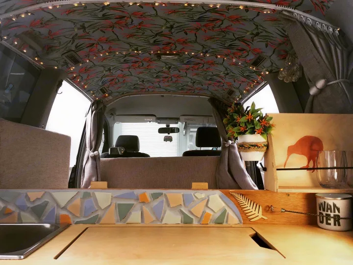 Stylish rv rental van interior with custom leaf-patterned ceiling, mosaic kitchenette, and cozy decor.. Toyota Noah 2005