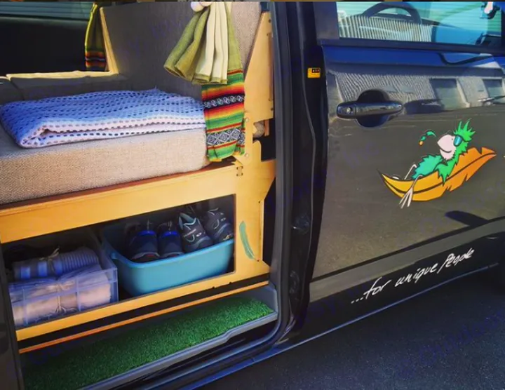 This RV rental showcases a custom camper van interior: cozy bed, organized under-bed storage for shoes & items, plus a fun door decal.. Toyota Noah 2005