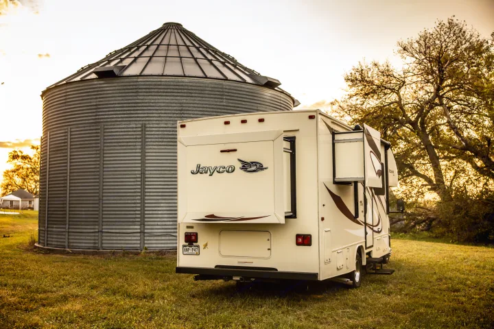 Jayco RV rental motorhome with pop-outs open, parked beside a grain silo at sunset. Explore rural escapes!. Jayco Redhawk 2016