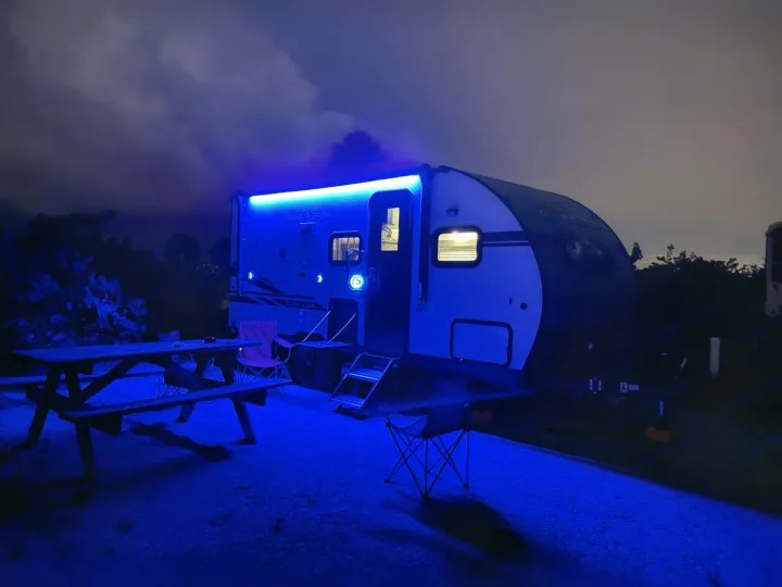Nighttime rv rental: blue-lit travel trailer, picnic table, and chairs at a vibrant campsite.. Forest River Cherokee Wolf Pup Black Label 2021