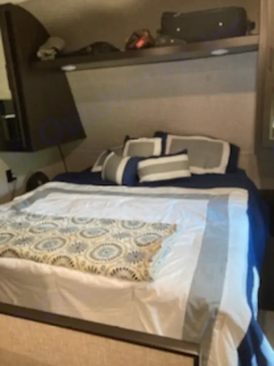 Experience comfort in this RV rental bedroom: a spacious bed with blue and white linens, overhead storage, ready for adventure.. Jayco Jay Flight 2022