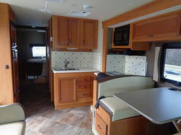 RV rental interior showcasing a well-equipped kitchen, cozy dinette, and a glimpse of the private bedroom area.. Holiday Rambler Admiral 2016