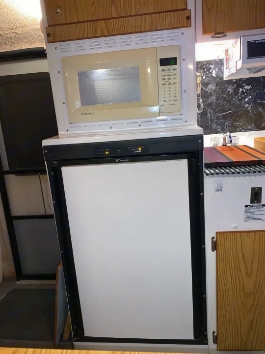 Inside this rv rental, a Dometic microwave and refrigerator are stacked in a compact kitchen setup.. Casita 17' Spirit Deluxe 2010
