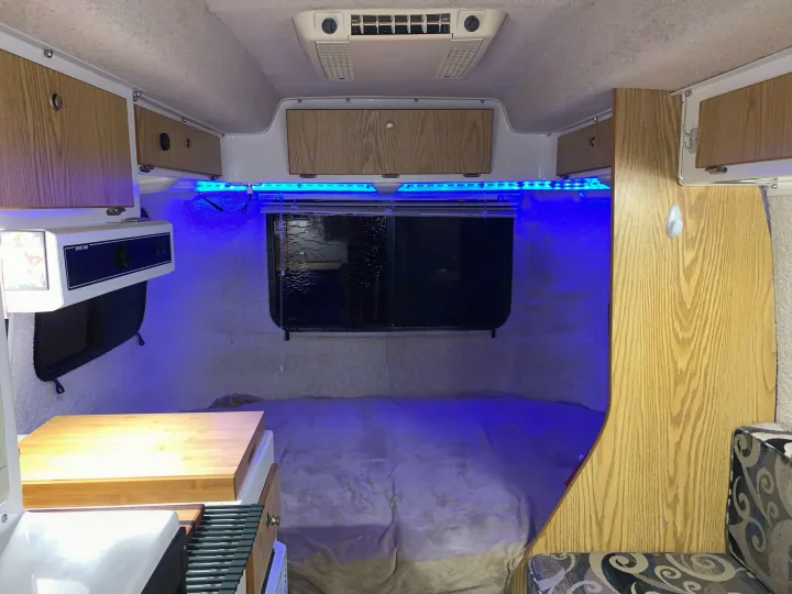 Inside a compact RV rental, featuring a bed, kitchen, storage, and striking blue accent lighting for cozy nights.. Casita 17' Spirit Deluxe 2010