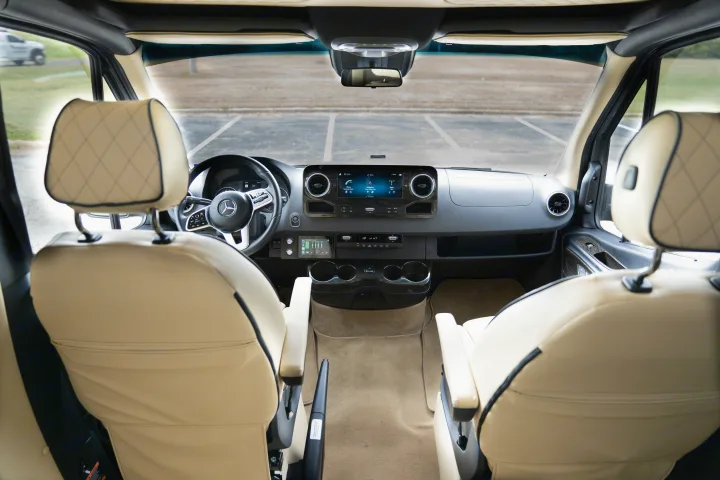 View inside a Mercedes-Benz RV rental. Luxury beige front seats, modern dashboard with infotainment for comfortable travel.. Ultimate Toys Ultimate Traveler 2022