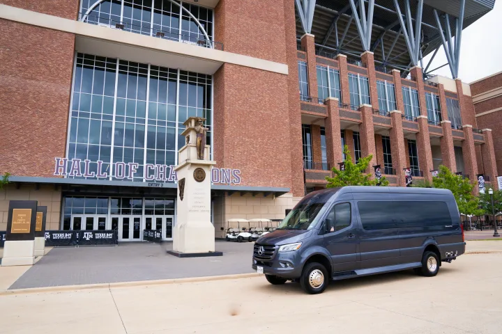 Luxury rv rental van parked at Texas A&M's Hall of Champions, showcasing the stadium's brick architecture.. Ultimate Toys Ultimate Traveler 2022