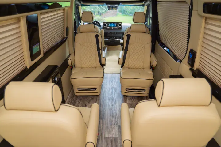 Spacious luxury **RV rental** interior: cream captain's chairs, wood floor, window blinds, & tech panels for ultimate comfort.. Ultimate Toys Ultimate Traveler 2022