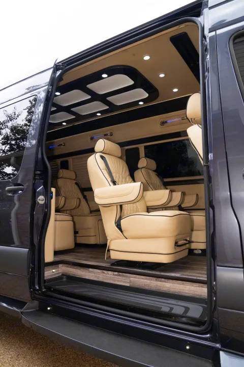 Explore a luxurious rv rental: plush beige leather captain's chairs, wood floor, and ambient lighting visible through the open side door.. Ultimate Toys Ultimate Traveler 2022
