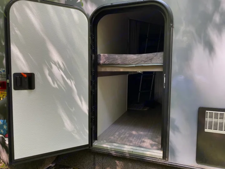 This RV rental's open side door reveals compact bunk beds, a ladder, and flooring inside. Great for travel!. Other Passport 2020