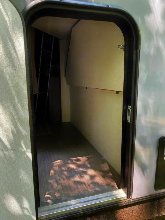 Step inside an RV rental! View of the interior showing a bunk bed ladder, an open storage area, and wood-look flooring.. Other Passport 2020