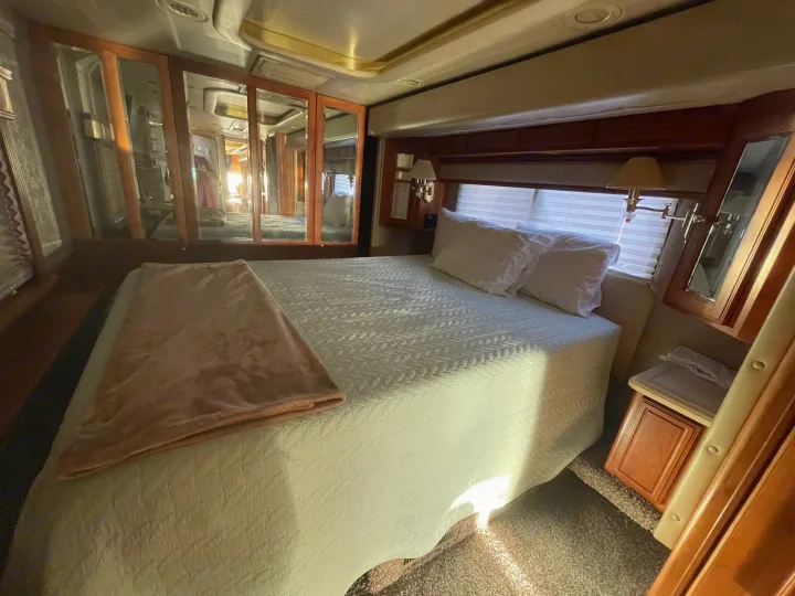 Comfortable RV rental bedroom with a large bed, mirrored cabinets, and ample natural light. Perfect for travel comfort.. Foretravel U-320 2001
