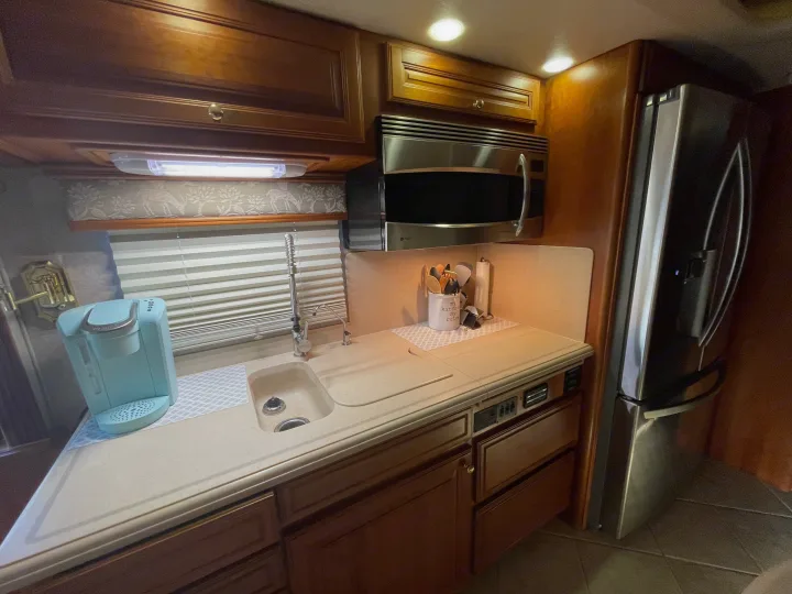 Cozy RV rental kitchen featuring wood cabinets, sink, microwave, fridge, and Keurig for convenient travels.. Foretravel U-320 2001