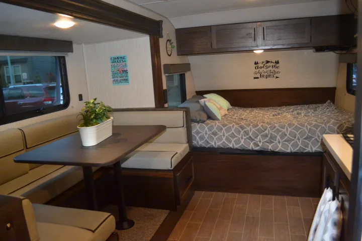 Spacious RV rental interior with a comfy dinette, bed, and overhead cabinets, perfect for camping trips.. Forest River Cherokee Wolf Pup 2020