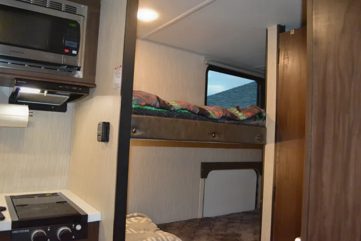 This RV rental features a compact kitchen with microwave and stove, plus cozy bunk beds, offering home-like amenities.. Forest River Cherokee Wolf Pup 2020