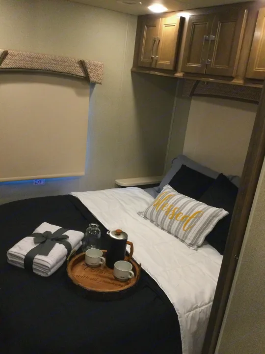 Cozy RV rental bedroom: bed with "Blessed" pillow, coffee tray, and neatly folded towels for a comfortable stay.. Jayco Greyhawk 2018