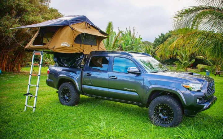 Gray pickup with a Pitmast rooftop tent & ladder on grass. A great RV rental alternative for camping & outdoor adventures.. toyota tacoma 2021