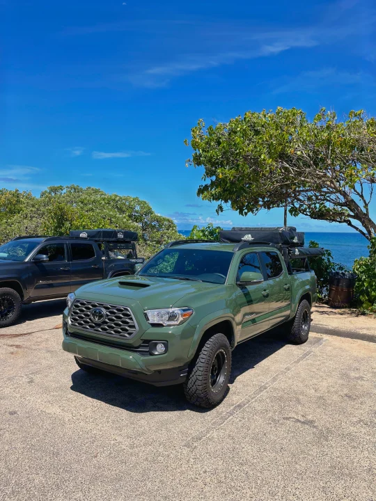 Two overlanding Toyota Tacomas with rooftop tents parked by the ocean. Experience a unique RV rental alternative for camping!. Toyota Tacoma 2021