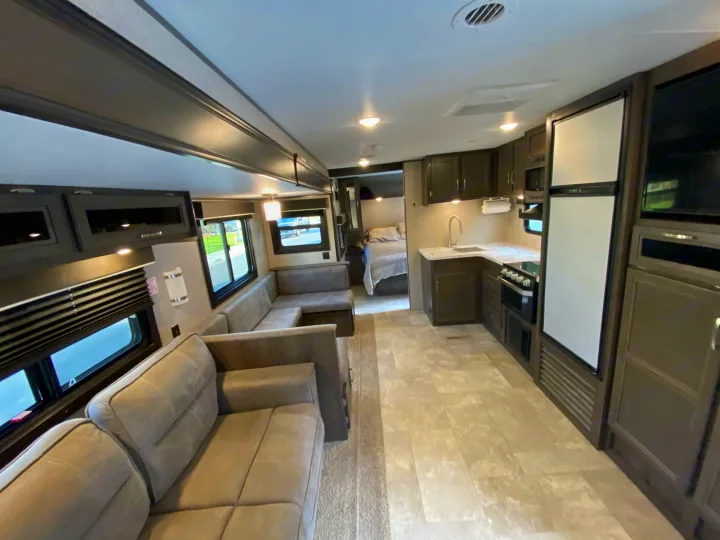 Spacious RV rental interior featuring a modern living area with a large sofa, a full kitchen, and a bedroom.. Jayco Jay Flight 2020