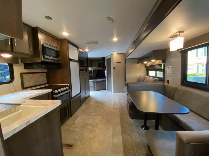 Explore this modern RV rental's spacious interior, featuring a well-equipped kitchen, comfortable dining, and cozy bunk beds.. Jayco Jay Flight 2020