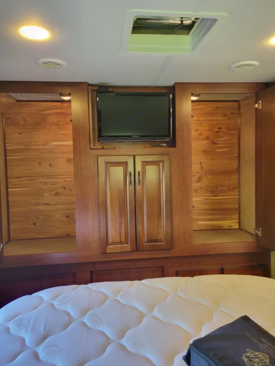 Inside an RV rental: a cozy bedroom features a Serta mattress, built-in cedar storage wardrobes, and a mounted TV.. Forest River Forester 3011DS 2015