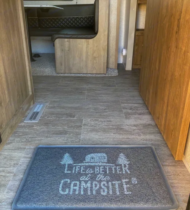 RV rental interior: gray floor, "Life is Better at the Campsite" mat, and a cozy dinette area. Ready for adventure!. Dutchmen Aspen Trail 2020