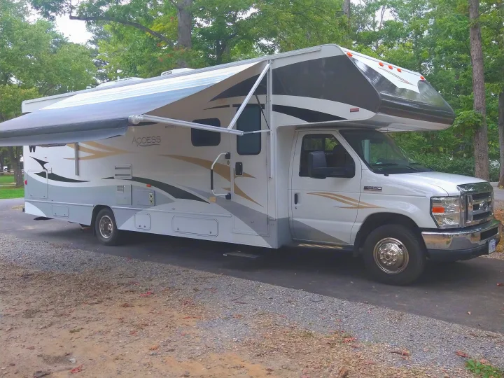 White Access Class C RV with extended awning, ready for your next rv rental adventure. Parked on a gravel & paved site.. Winnebago Access 2011