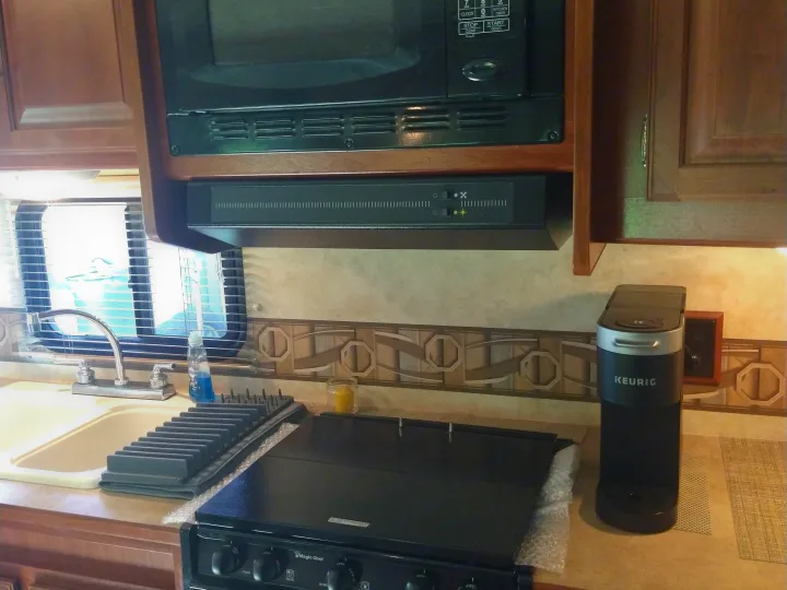 Well-equipped RV rental kitchen featuring a microwave, range, sink, and Keurig, perfect for your travels.. Winnebago Access 2011