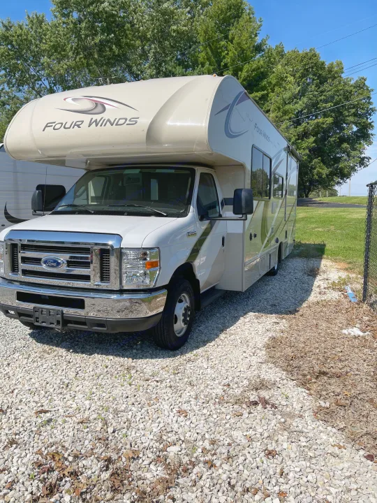 This white Four Winds Class C RV rental is parked on a gravel lot, ready for your travel adventure.. THOR FOUR WINDS 26 B 2021