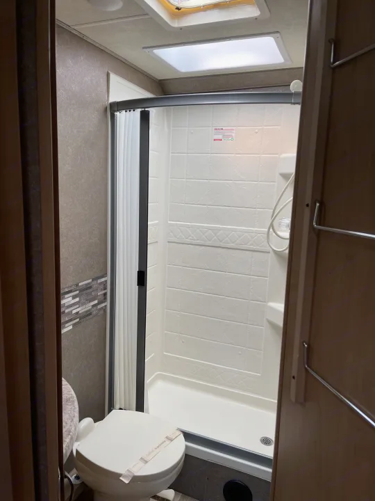 This RV rental features a clean, compact bathroom with a modern shower and a sanitized toilet, ready for your road trip.. THOR FOUR WINDS 26 B 2021