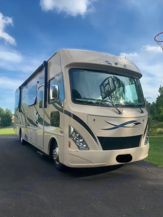 A large beige ACE RV motorhome, ideal for an RV rental, is parked on an asphalt driveway under a blue sky.. Thor Motor Coach A.C.E 2017