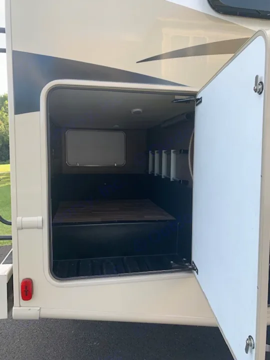 Spacious RV rental exterior storage bay shown open, revealing deep compartment, inner access hatch, and shelving.. Thor Motor Coach A.C.E 2017