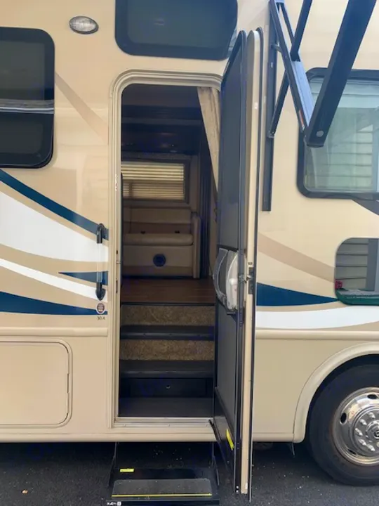 This RV rental motorhome's open side door reveals interior steps & living area. An awning extends above. Ready for your adventure!. Thor Motor Coach A.C.E 2017