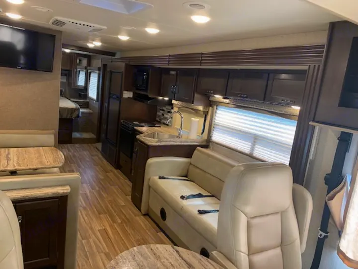 Explore this RV rental's spacious interior: kitchen, dinette, living space, and elevated sleeping area.. Thor Motor Coach A.C.E 2017