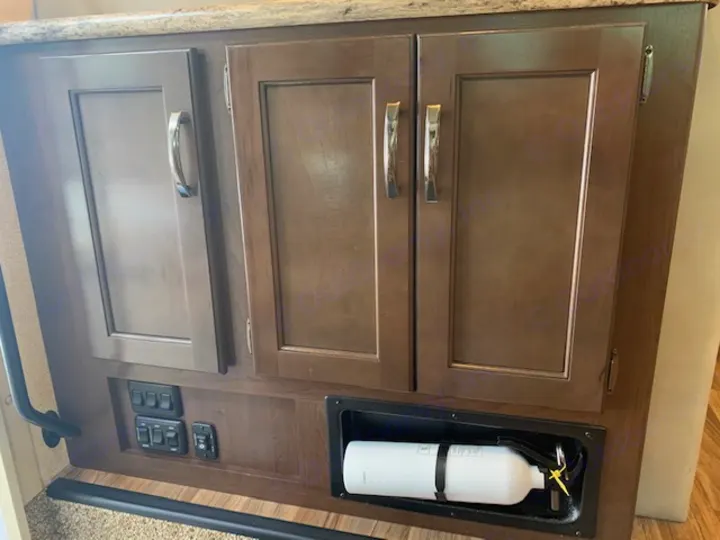 Inside your RV rental: Fire extinguisher, control panel switches, and storage cabinets for safety and convenience.. Thor Motor Coach A.C.E 2017