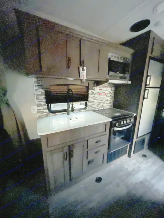 RV rental: Modern RV kitchen featuring dark wood cabinets, a sink, stove, microwave, and refrigerator.. Forest River Shockwave 2021