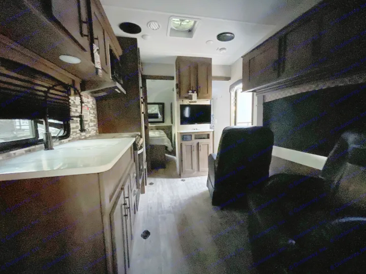 Modern RV rental interior showing a well-equipped kitchen, comfortable living space with recliners, and light-toned flooring.. Forest River Shockwave 2021