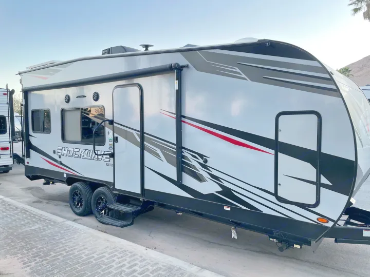 Modern grey & white Shockwave RV rental: a sporty travel trailer with black & red graphics and an awning.. Forest River Shockwave 2021