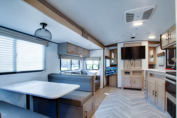 Inside a modern RV rental: light-filled living space with dinette, kitchen, entertainment center, and herringbone flooring.. Cruiser Rv Corp Shadow Cruiser 2021