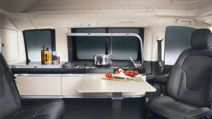 This RV rental interior features a functional camper van kitchen with stove, sink, and extendable table, perfect for culinary adventures.. Mercedes Class V Marco Polo 2021