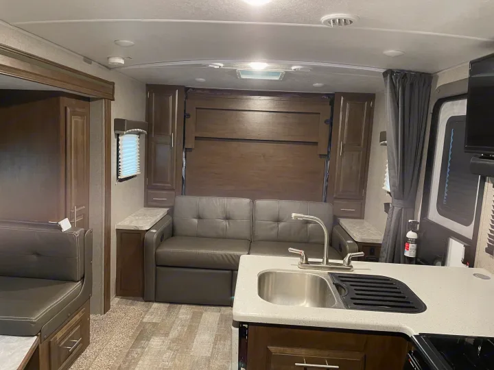 Inside this modern RV rental: a compact kitchen, pull-out sofa or murphy bed setup, and dinette for cozy living on the road.. Forest River Rockwood Mini Lite 2020