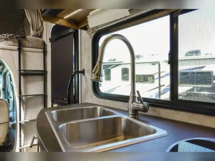 Inside an RV rental: modern kitchen with double sink, sleek faucet, and adjacent bunk bed.. Winnebago View 2018