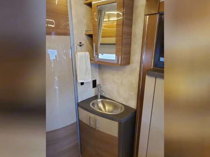 Inside an RV rental, a compact bathroom vanity features a sleek sink, faucet, cabinet, and mirrored medicine cabinet.. Winnebago View 2018