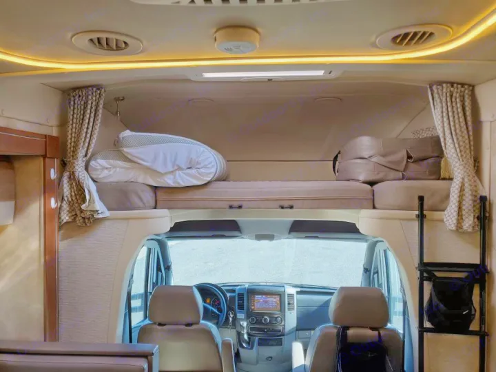 Inside an RV rental: View from the living area showing the front cab with dashboard and overhead bunk with bedding.. Winnebago View 2018