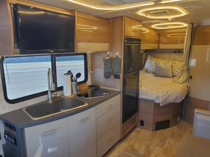 This RV rental offers a modern interior with a well-equipped kitchen, comfortable bedroom, and entertainment TV.. Winnebago View 2019