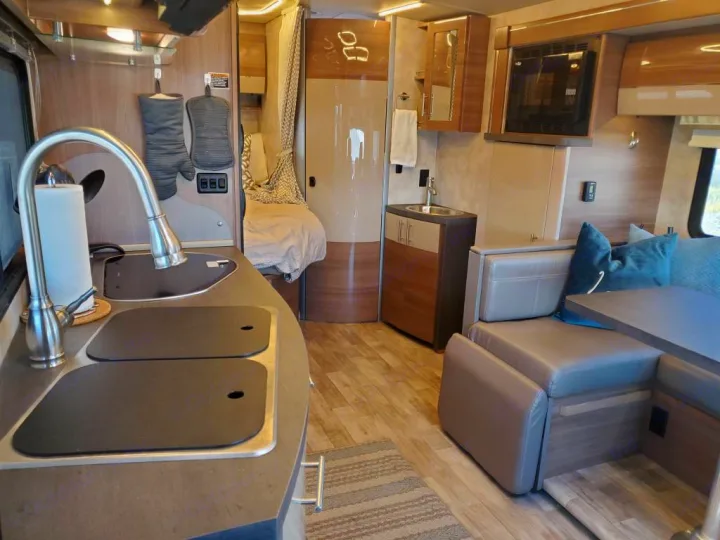 Modern RV rental interior showcasing a kitchen, living space with sofa, and rear bed for comfortable travel.. Winnebago View 2019