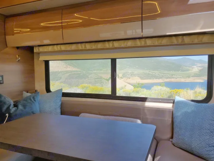 Stunning lake and mountain views from inside an RV rental! Relax in the dining area with blue pillows and modern cabinets.. Winnebago View 2019