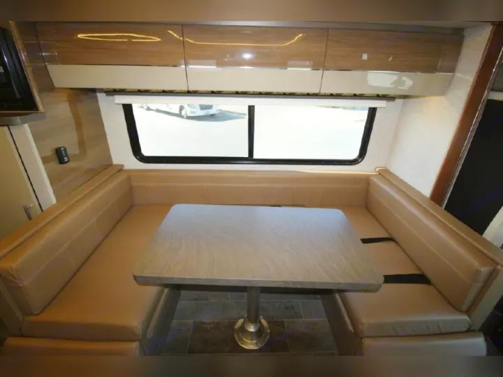 RV rental dinette area featuring comfy tan booth seating, a table, and overhead cabinets, perfect for meals.. Winnebago View 2019