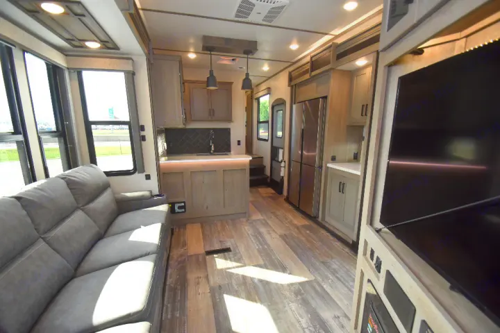 Spacious, modern RV rental interior featuring a comfortable sofa, full kitchen, and large entertainment TV.. Keystone Raptor 2025